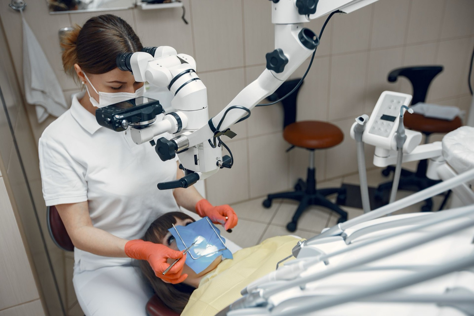 A dentist in a mask treating a patient in a modern dental clinic