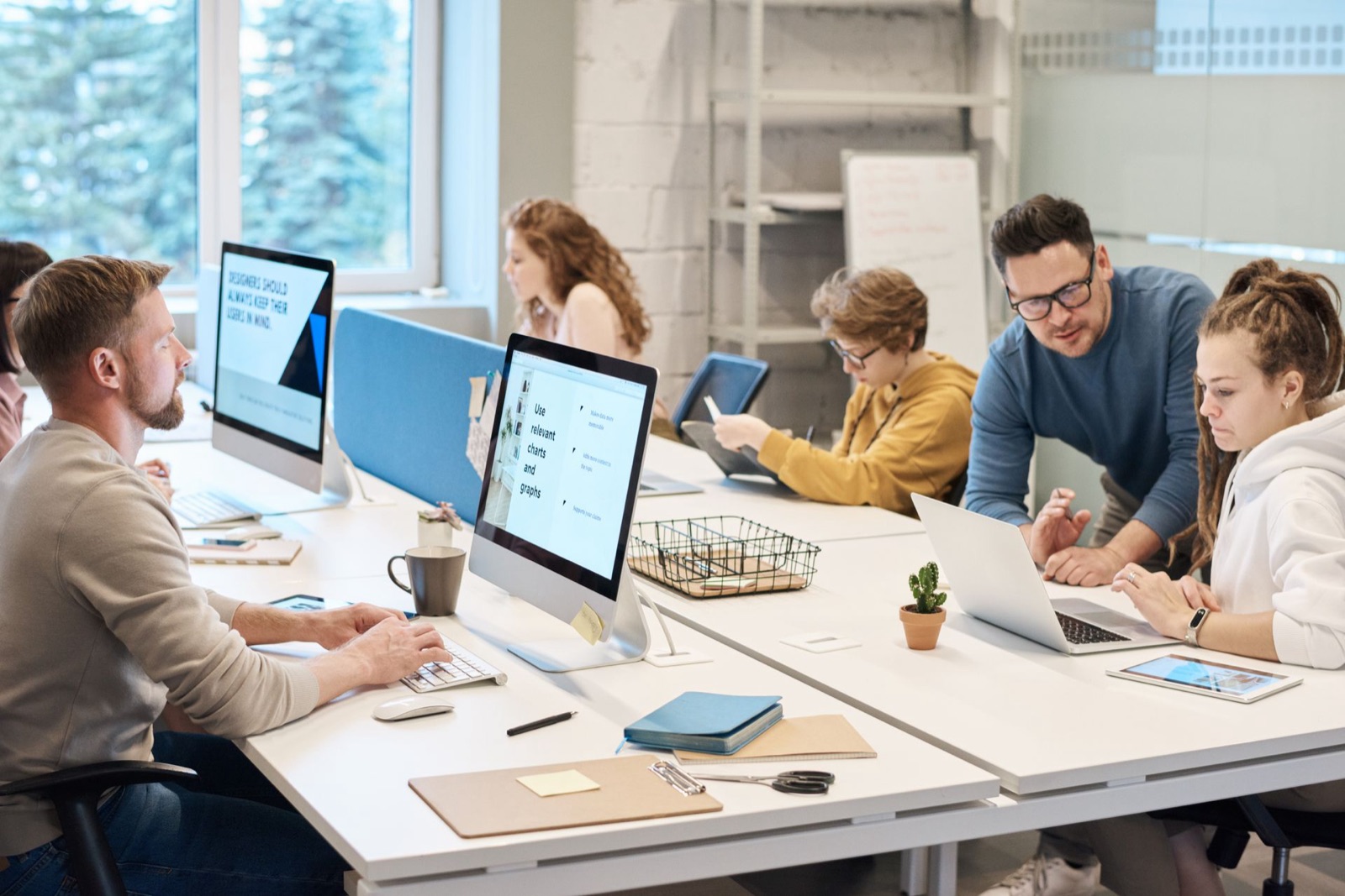 A marketing team working together at computers in a bright open office