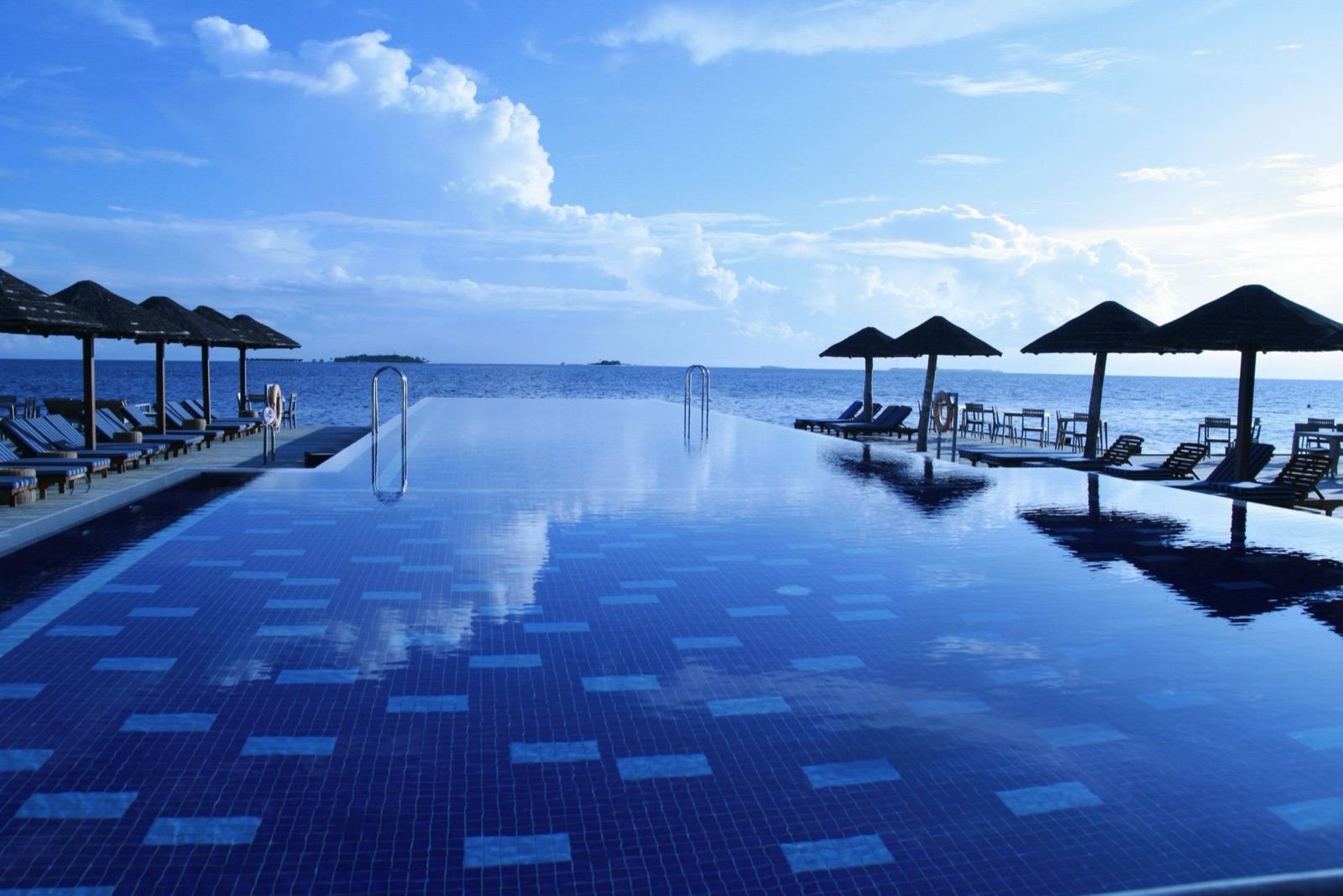 An infinity pool with lounge chairs and umbrellas at a beachfront resort