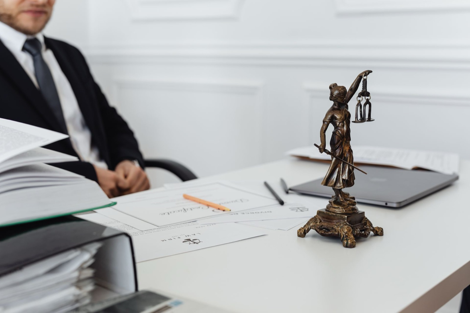A lawyer at his desk with a scales of justice statue and case files