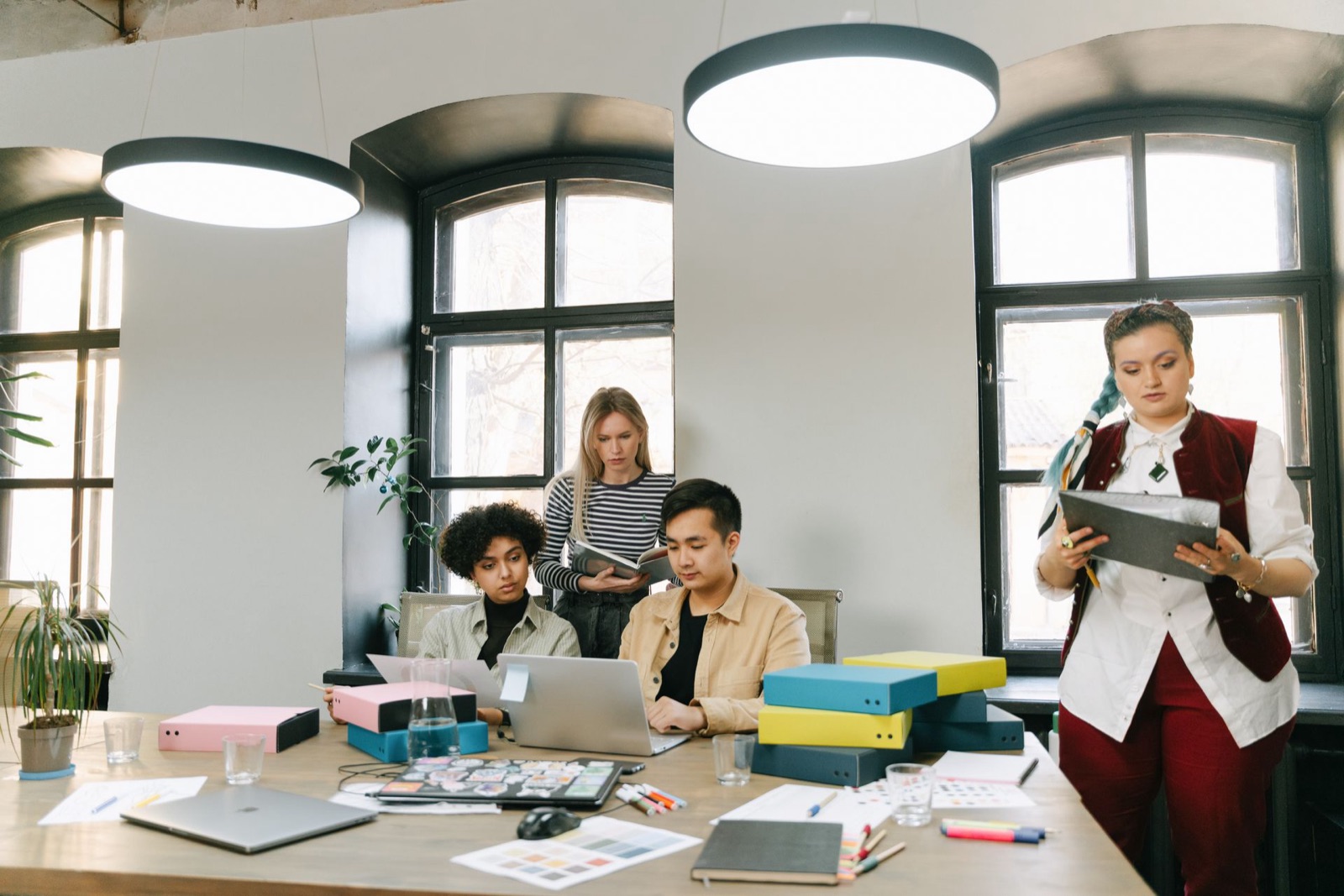 A young startup team working together around a table covered in notes and laptops