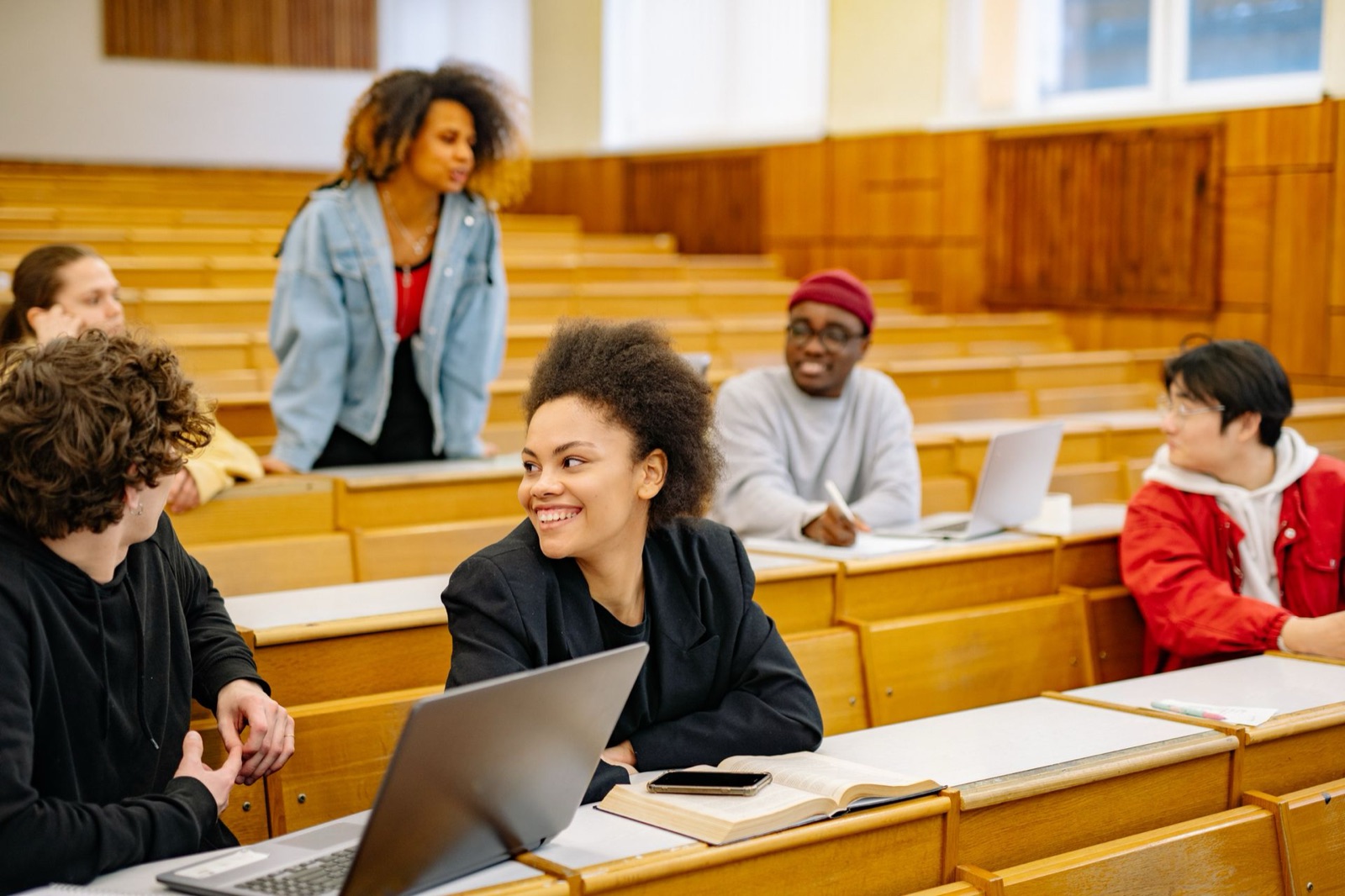 Students talking between rows of desks in a university lecture hall