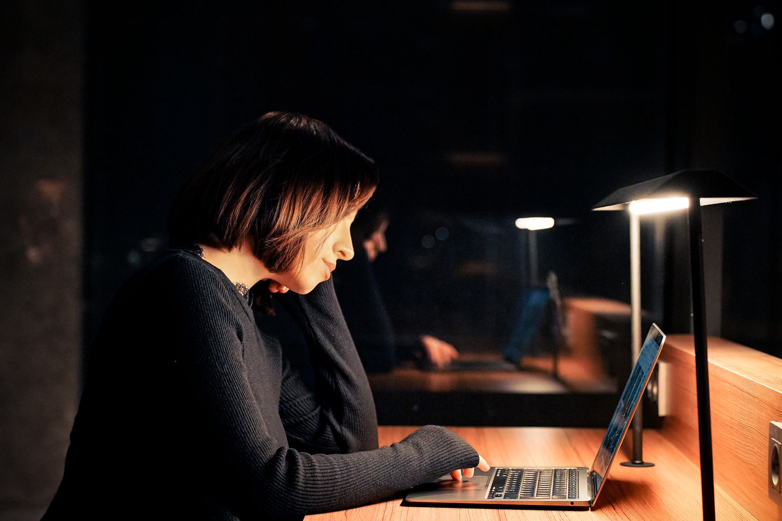 A person working on a laptop in a dimly lit reading room