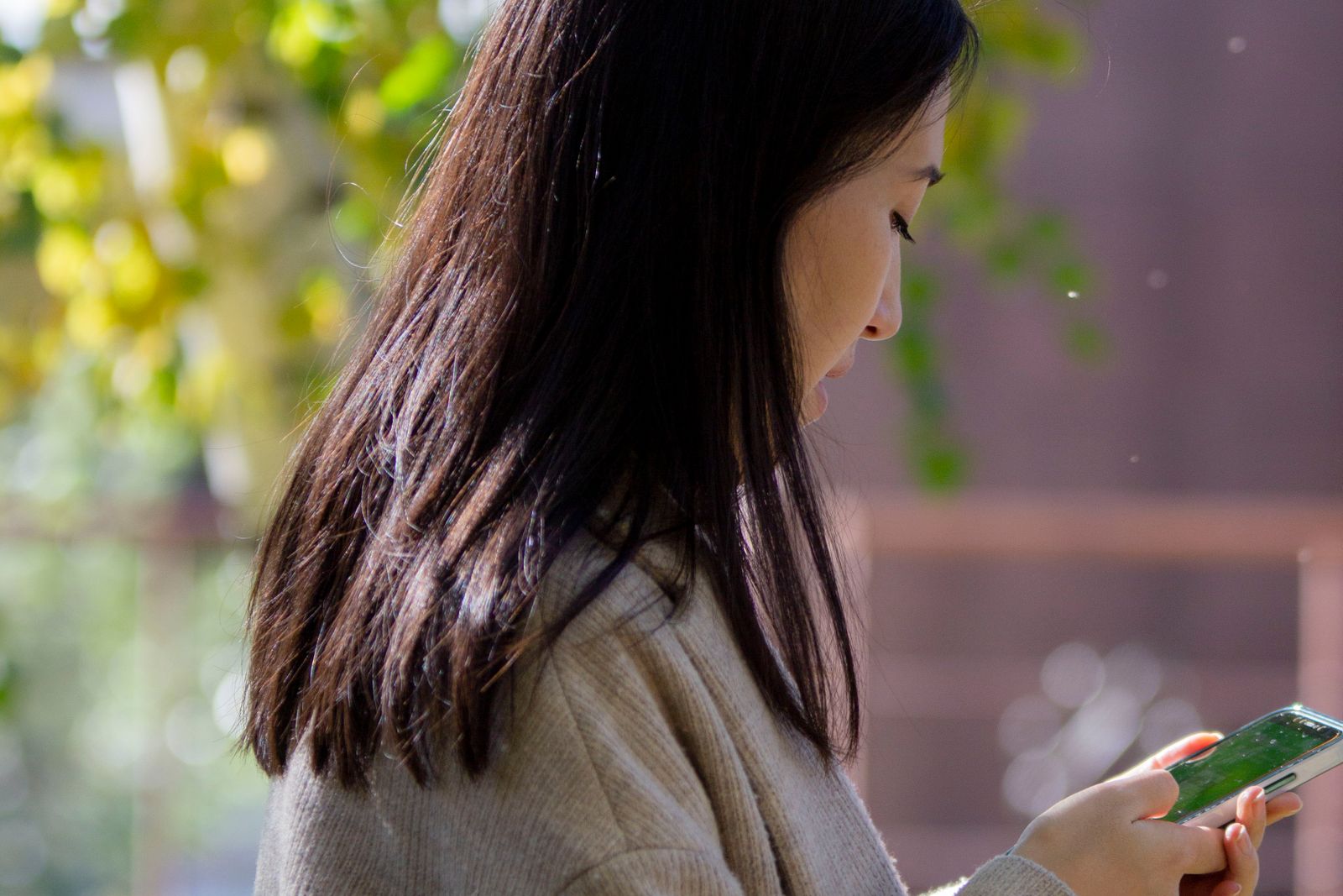 Woman in glasses checking her phone while walking outside on a fall afternoon