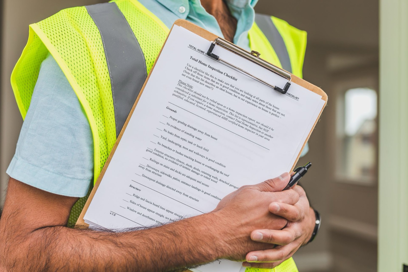 An adjuster in a safety vest holding a home inspection checklist on a clipboard