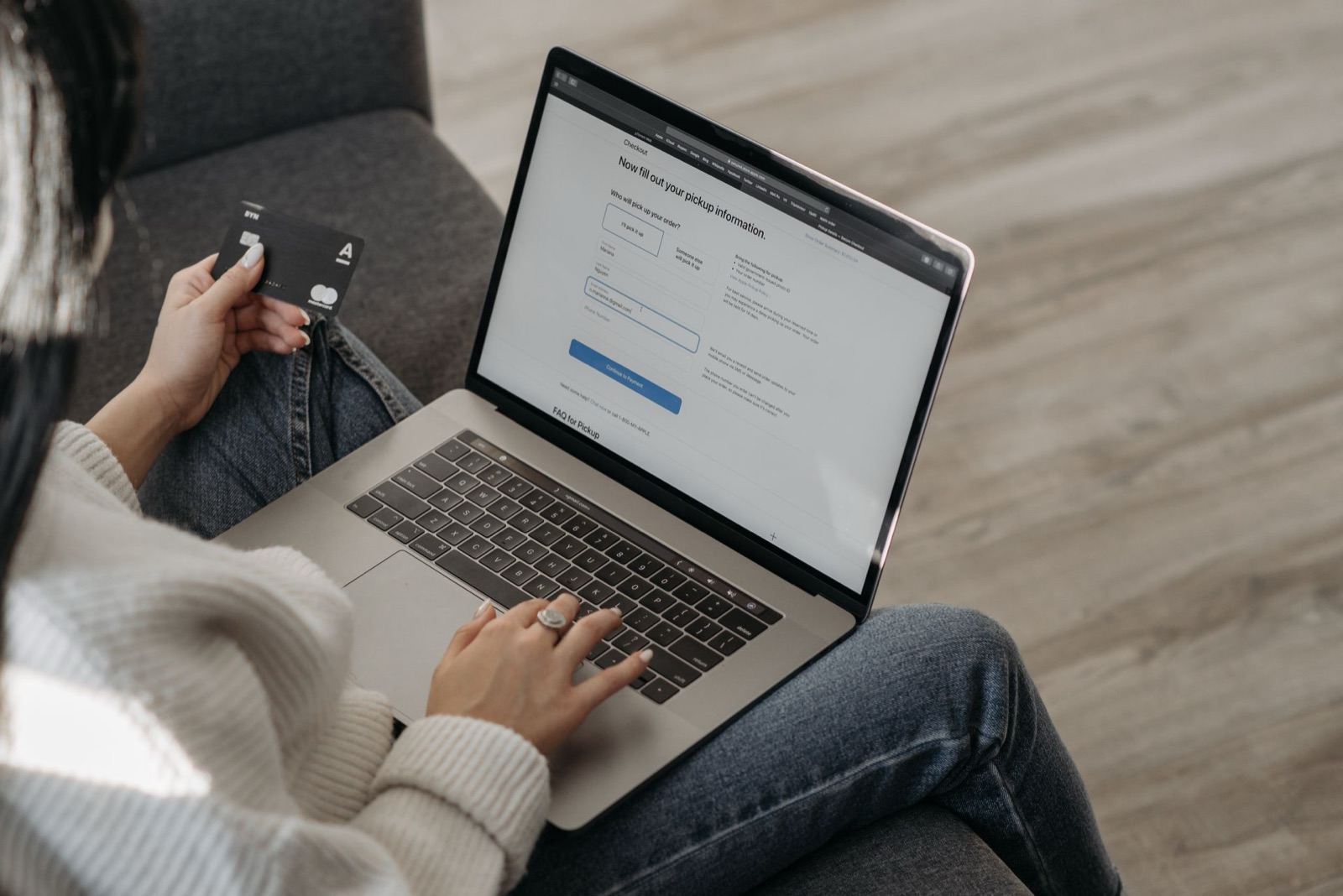 A shopper holding a credit card while completing an online checkout on a laptop