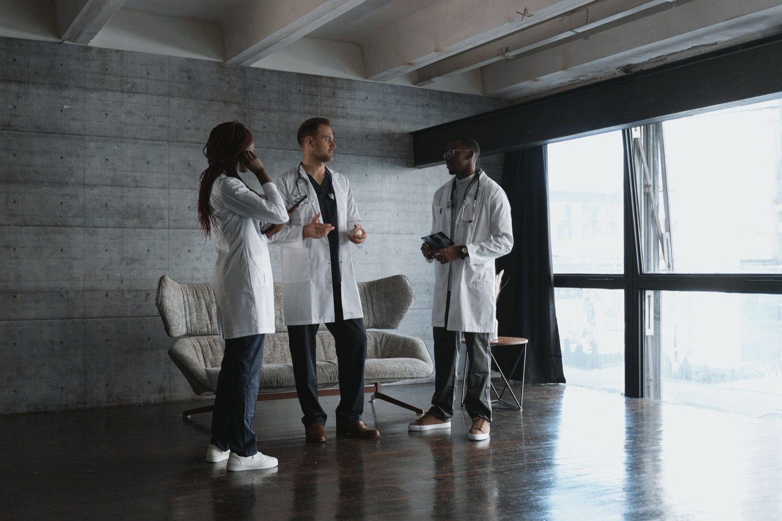 Three doctors in white coats talking through plans at their practice