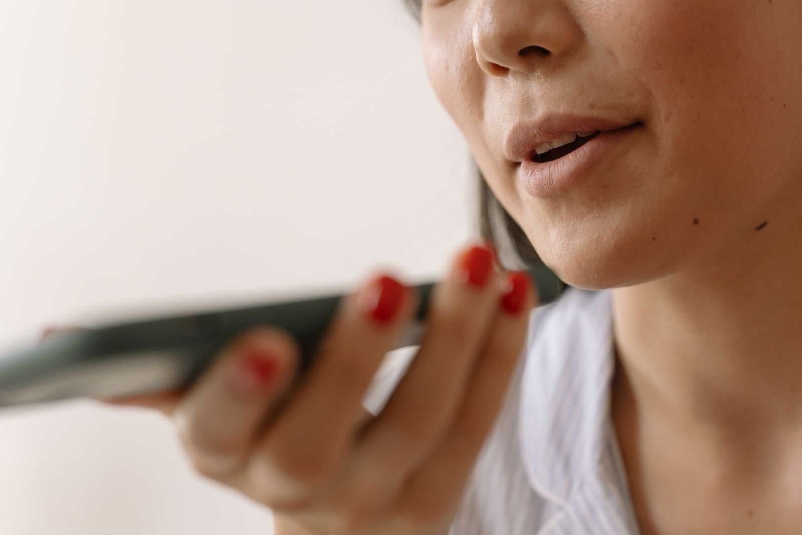 A woman speaking into her phone, asking a voice assistant a question