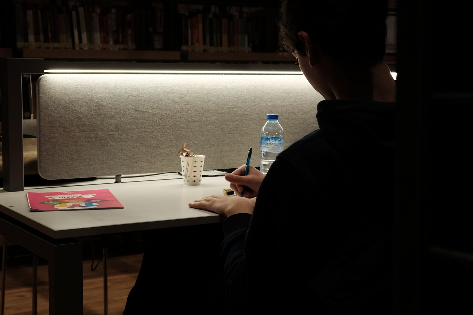 Person Sitting in Darkness by Table and Writing