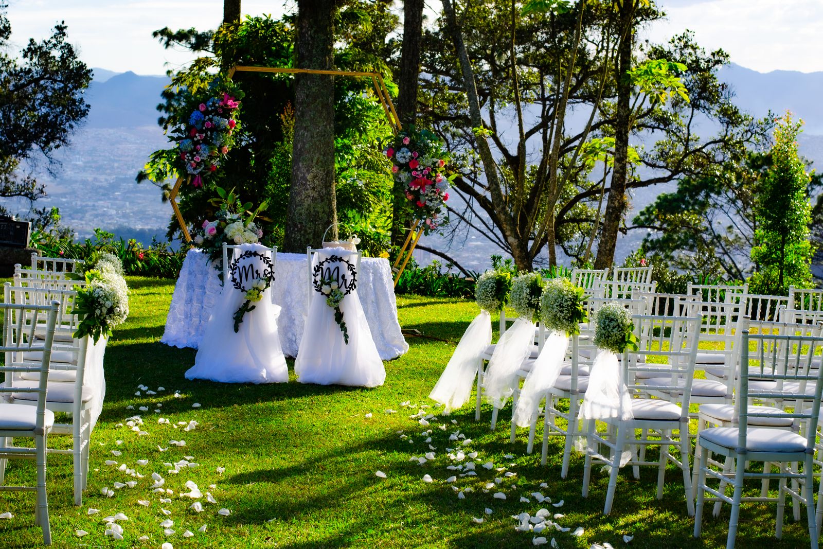 An outdoor wedding ceremony set with white chairs along the aisle