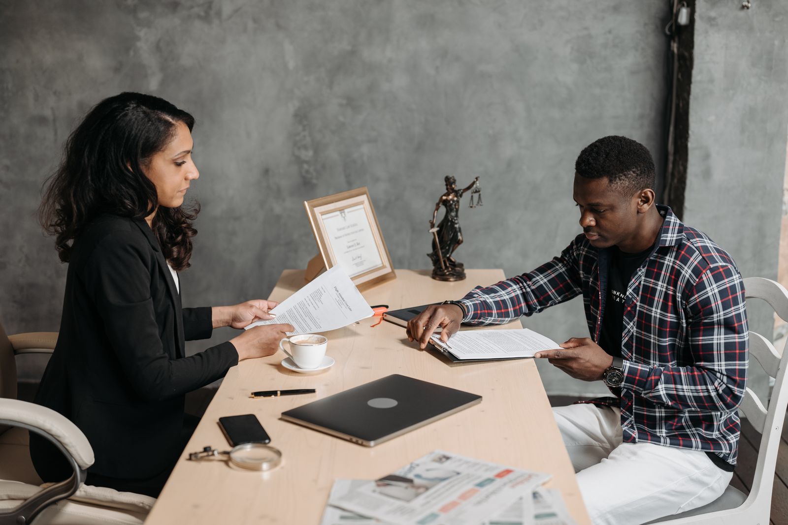 Attorney and consultant reviewing a marketing plan on a laptop beside the scales of justice