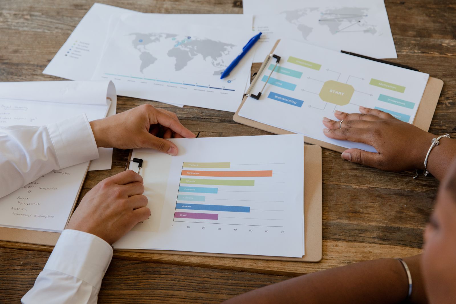Two colleagues reviewing printed performance charts on a table