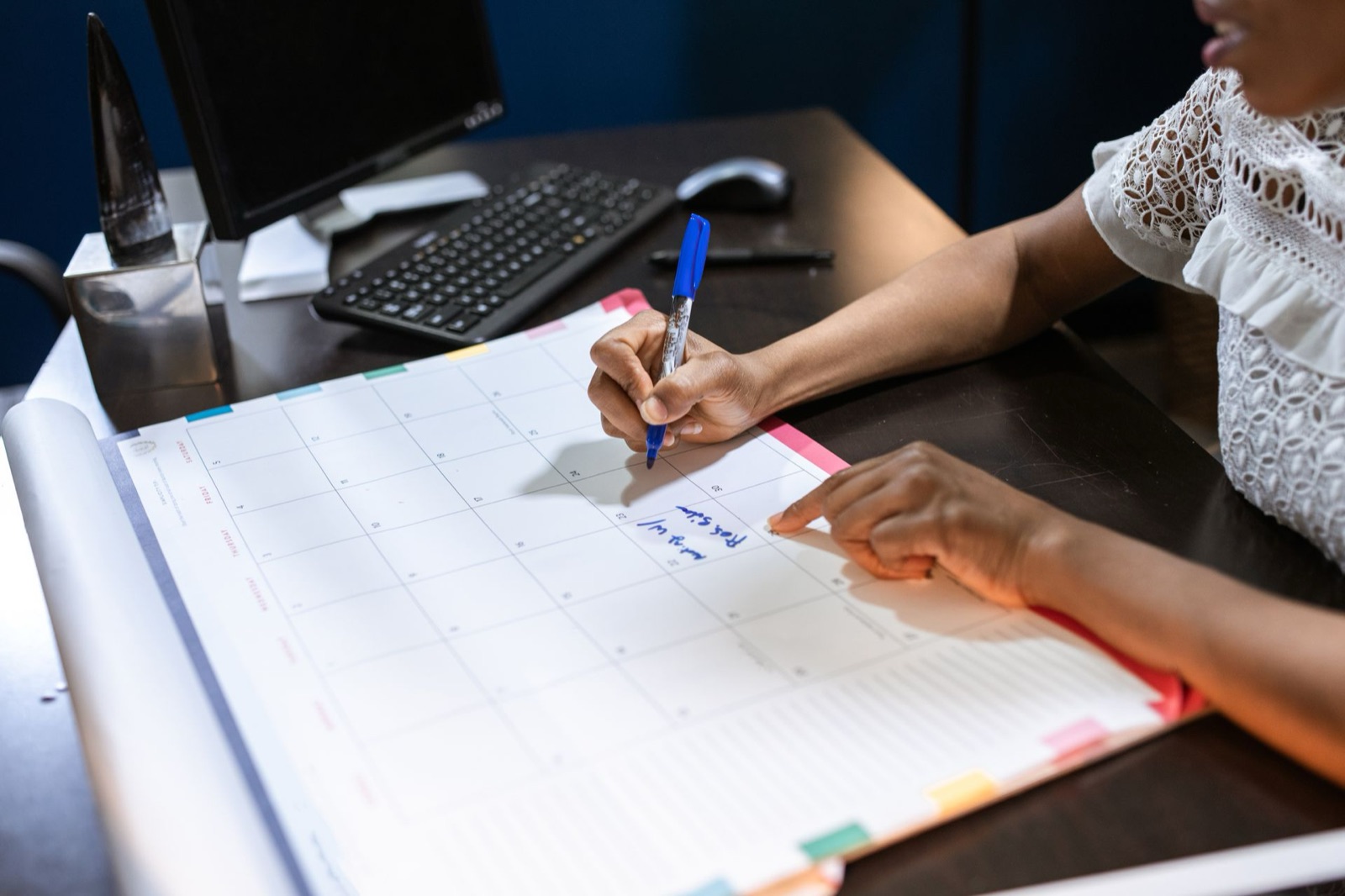 A staff member writing appointments into a desk calendar at an office