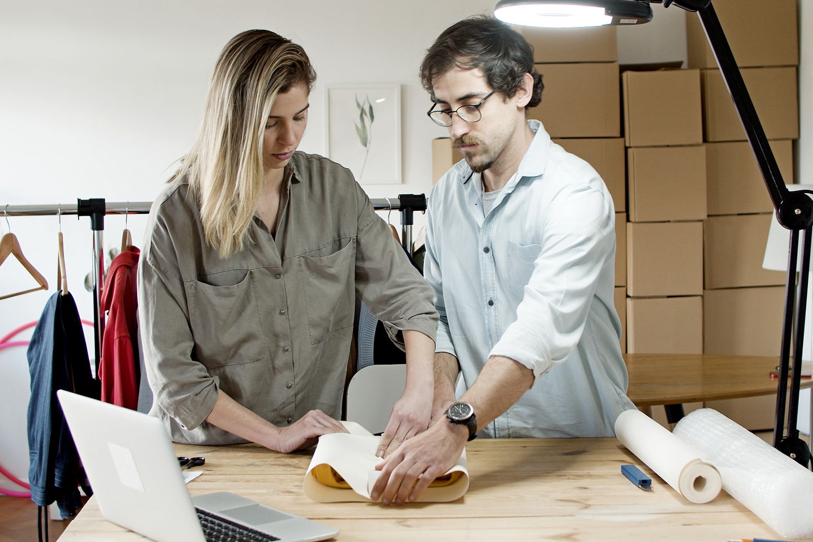 An online shop owner packing orders beside a laptop