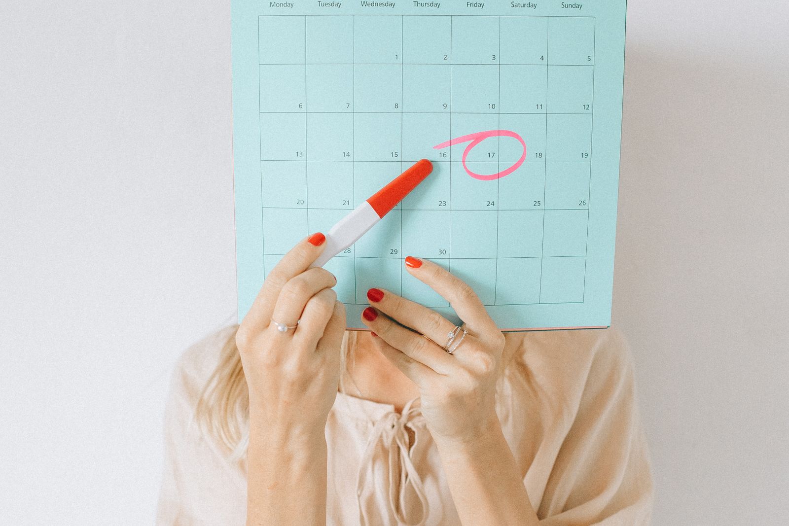 Hands marking dates in a paper planning calendar next to a laptop
