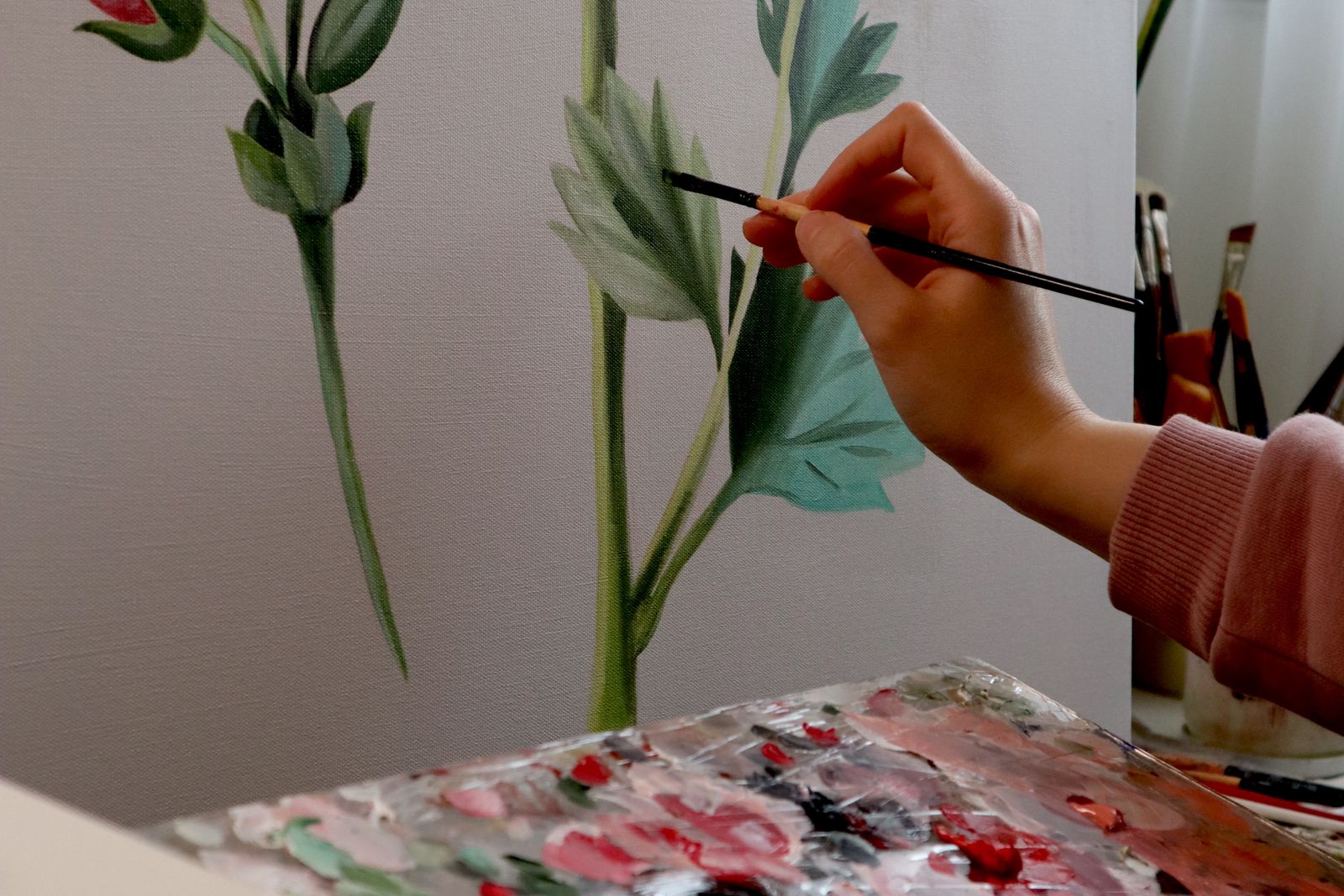 An artist painting flowers in watercolour beside her work table