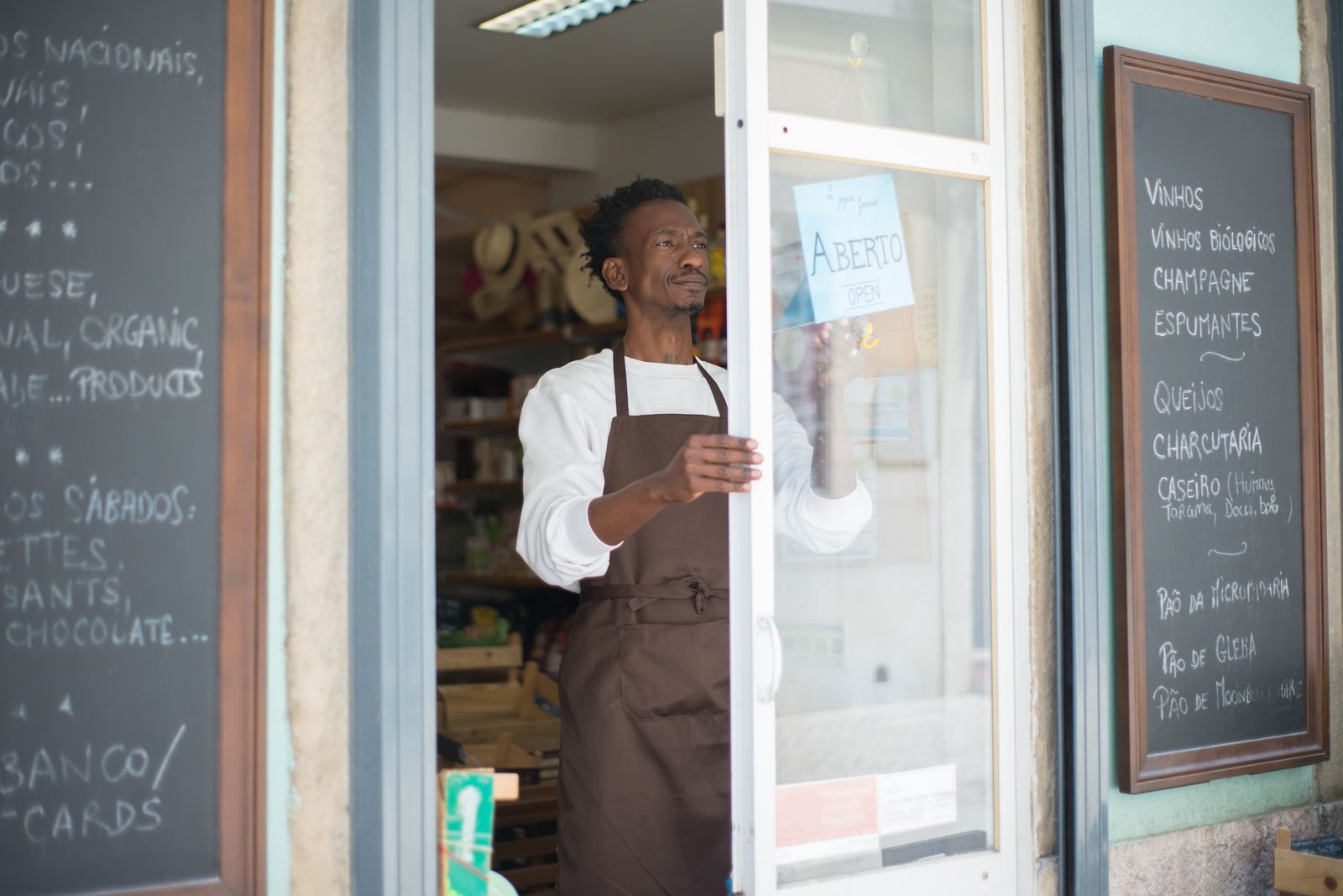 A shop owner in an apron opening his store for the day