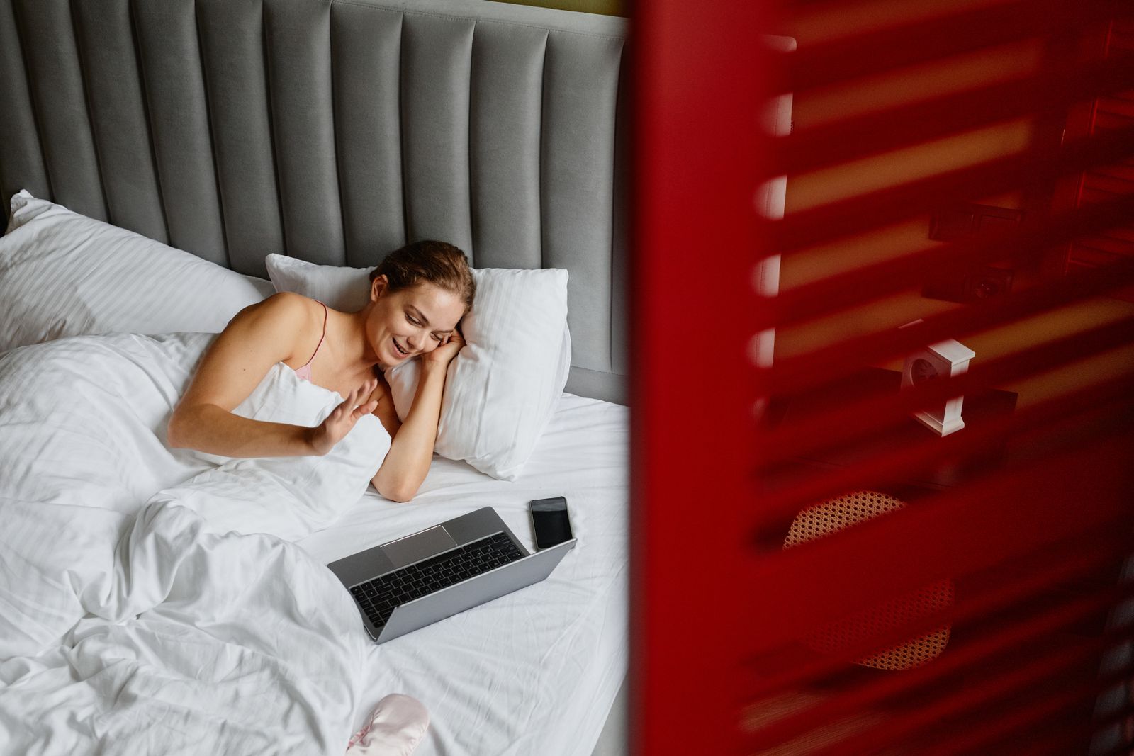Business traveler booking her next stay on a laptop from a hotel room bed