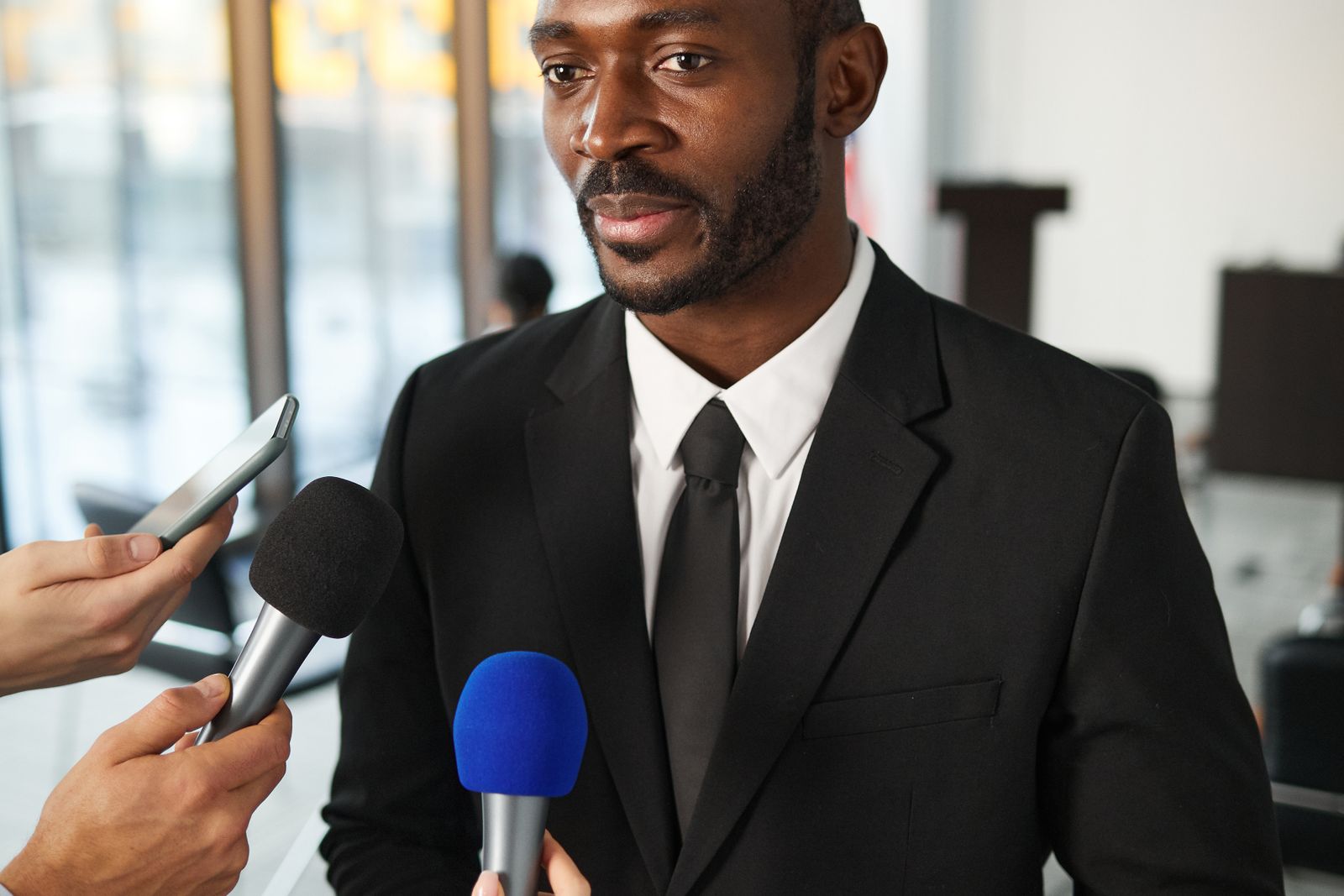 A spokesperson answering questions into a cluster of press microphones