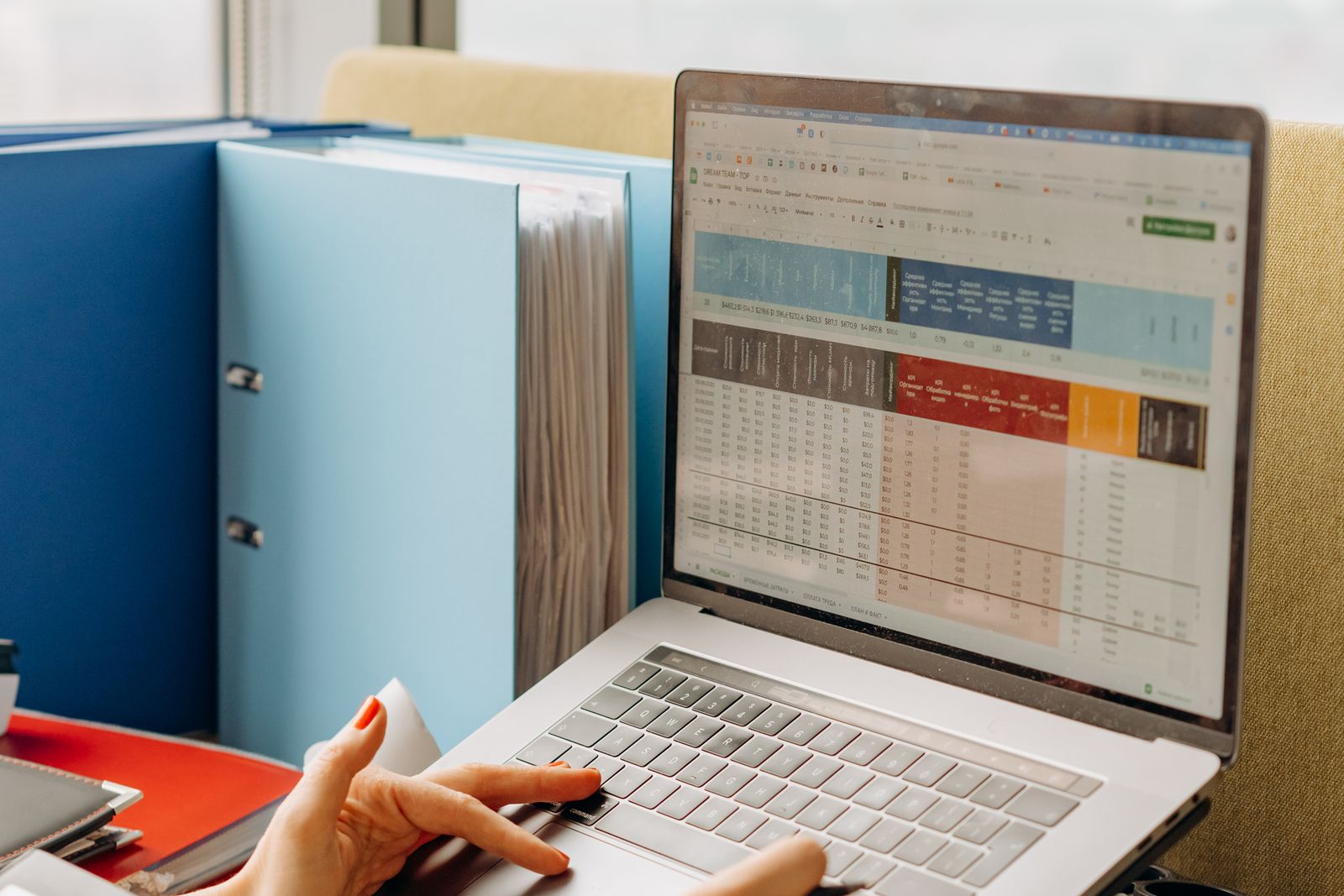 A spreadsheet open on a laptop beside labelled folders