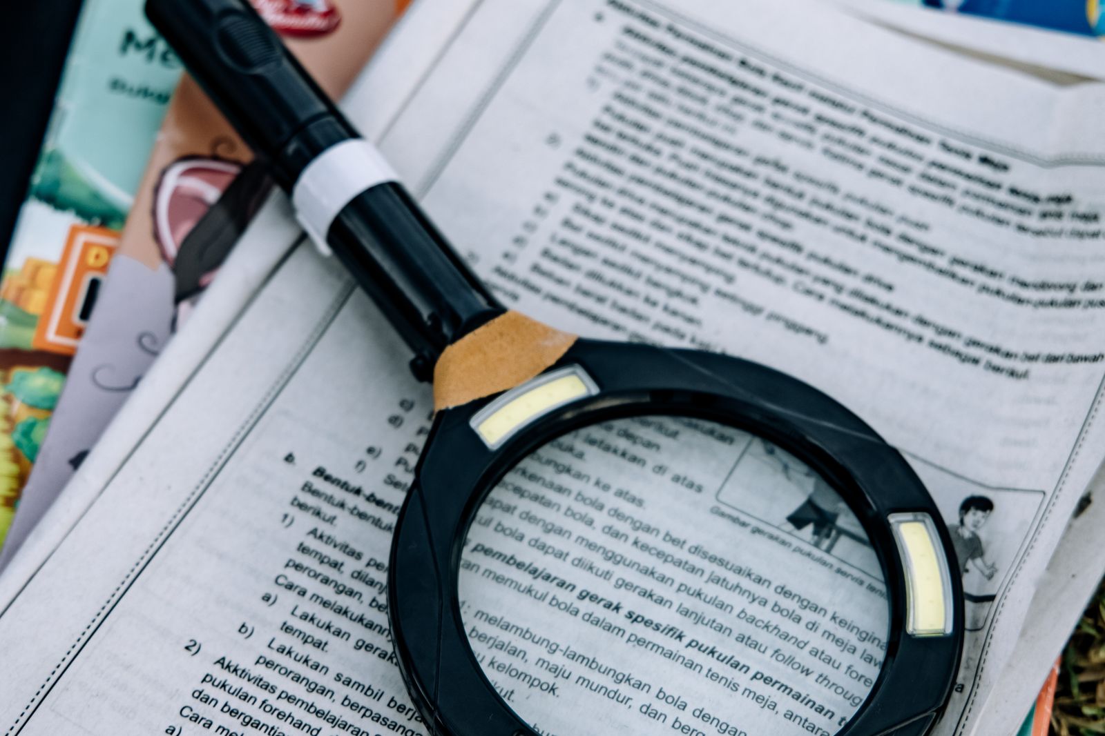 A magnifying glass resting over printed pages of text