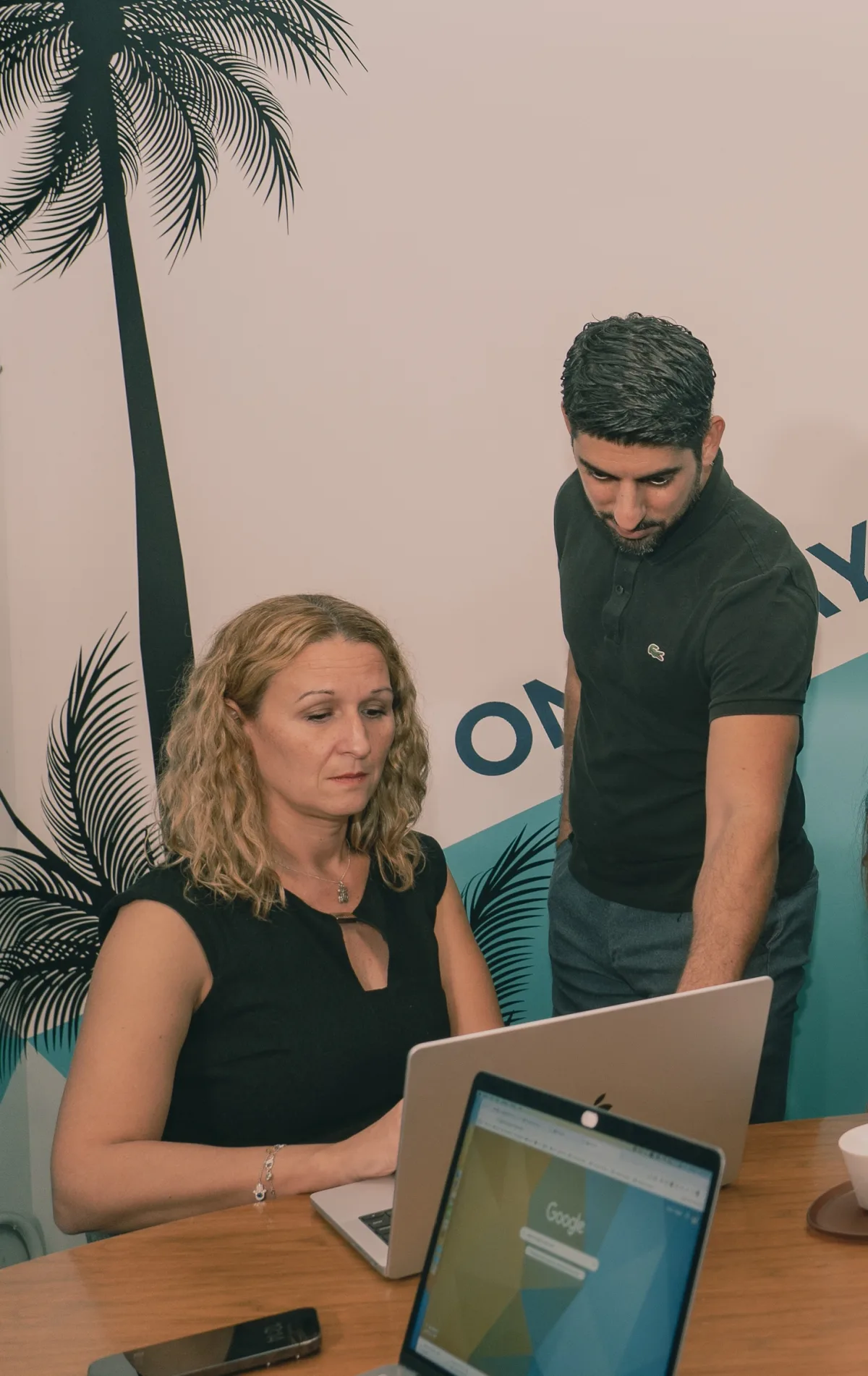 Two Pacific54 team members reviewing work together at a laptop